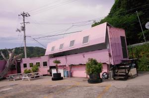 um edifício cor-de-rosa com piso aventh em 千代丸コンテナハウス em Uwajima