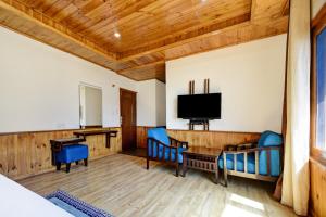 a living room with blue chairs and a television at OYO Itm Elysian in Vashisht