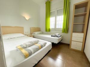 two beds in a room with green curtains at Bungalows Pescador in Segur de Calafell