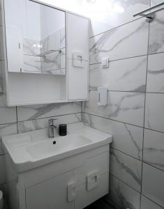 a white bathroom with a sink and a mirror at Paradosi Apartments in Igoumenitsa