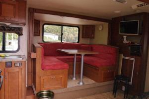 an interior of an rv with red seats and a table at 千代丸コンテナハウス in Uwajima