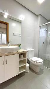a bathroom with a sink and a toilet and a shower at Belíssimo Apto com lareira e piscina aquecida! in Gramado