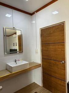 a bathroom with a sink and a wooden door at MJ RESORT in Nong Phai