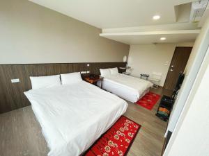 a hotel room with two beds and a red rug at 可青大飯店Grand Ke-Cing Hotel in Yilan City