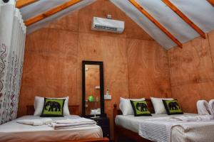 two beds in a room with wooden walls at Akash Treehouse in Sigiriya