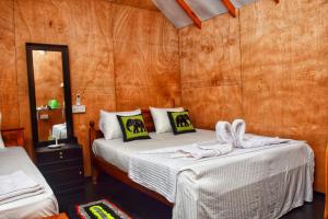 a bedroom with two beds in a room with wooden walls at Akash Treehouse in Sigiriya