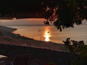 a sunset over a body of water with a boat at Ethaleia Hotel in Moúdhros