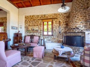 a living room with pink chairs and a stone wall at Ethaleia Hotel in Moúdhros