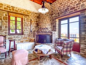 a living room with a fireplace and a stone wall at Ethaleia Hotel in Moúdhros