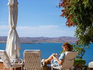 a woman sitting in lawn chairs by the water at Ethaleia Hotel in Moúdhros