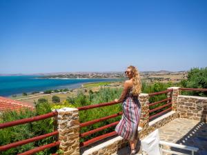 a woman standing on a fence looking out at the water at Ethaleia Hotel in Moúdhros
