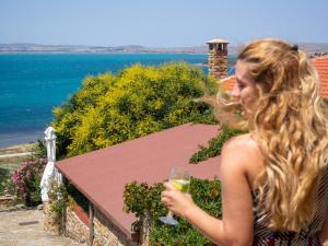 a woman holding a glass of wine on a balcony at Ethaleia Hotel in Moúdhros