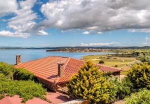 a house with a red roof and a lake at Ethaleia Hotel in Moúdhros