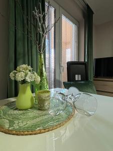 einen Tisch mit einer grünen Vase und Blumen darauf in der Unterkunft Apartmani "MARIJA" Golubac in Golubac