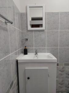 uma casa de banho com um lavatório branco e um espelho. em Coral Cottage em Hilton