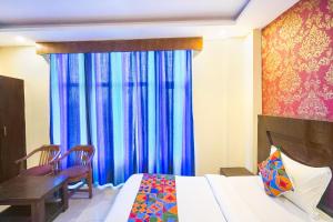 a bedroom with a bed and a window with blue curtains at FabHotel Green view palace in Indirapuram