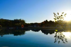 a pool of water with the sun setting in the background at El Pao Spa in Jijona