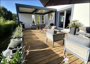 une terrasse en bois avec des chaises et des tables sur une maison dans l'établissement Villa Elias, pour séjours familiaux : Spacieuse, moderne, à La Baule