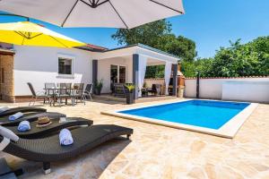 ein Pool mit Stühlen und einem Sonnenschirm und ein Haus in der Unterkunft Villa Lena in Pridraga