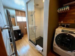 a bathroom with a washing machine and a glass shower at Hakuba Mountain Cabin in Hakuba