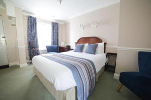 1 dormitorio con 1 cama grande y 1 silla azul en The Speech House, en Coleford