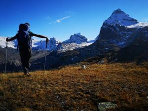 a woman walking on a hill with mountains in the background at Le Village De Fours in Rhêmes-Notre-Dame