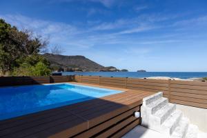 a swimming pool with a wooden deck and the ocean at 瀬戸内 TABITO in Yoshimi