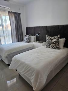 2 bedden in een hotelkamer met een nachtrok bij Grey Net in Palatswe