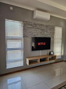 een woonkamer met een flatscreen-tv aan de muur bij Grey Net in Palatswe