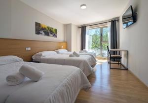 a hotel room with three beds and a window at Duerming Villa de Arzúa in Arzúa