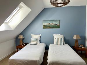 - 2 lits dans une chambre aux murs bleus dans l'établissement Villa Elias, pour séjours familiaux : Spacieuse, moderne, à La Baule