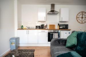 cocina con armarios blancos y sala de estar con sofá en Corporate-Friendly 2BR Apartment in Leeds, Near Kirkstall Shopping Centre, en Leeds