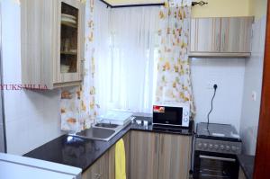 a small kitchen with a sink and a microwave at Yuks Villa in Kisumu