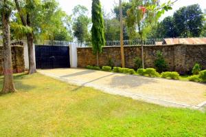 a yard with a stone wall and a fence at Yuks Villa in Kisumu