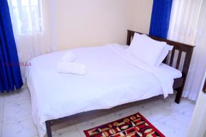una camera da letto con letto, lenzuola e cuscini bianchi di Yuks Villa a Kisumu