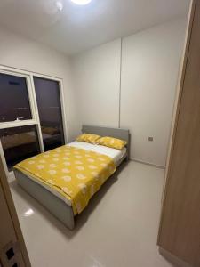 a bedroom with a bed with yellow sheets and a window at Apartmán Fiora, 2kk,Dubaj in ‘Ūd al Bayḑāʼ