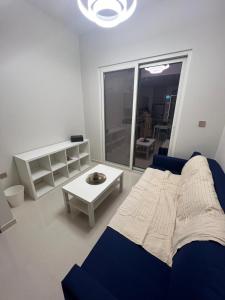 uma sala de estar com um sofá azul e uma mesa em Apartmán Fiora, 2kk,Dubaj em ‘Ūd al Bayḑāʼ