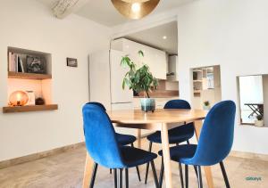 *Duplex Home Lambesc*Clim Garage في لامبيسك: غرفة طعام مع طاولة خشبية وكراسي زرقاء