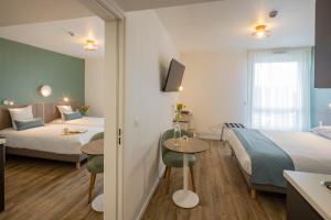 a hotel room with two beds and a table at All Suites Appart Hôtel - Le Havre Centre - Les docks in Le Havre