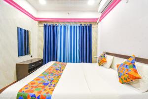 a bedroom with a large bed with blue curtains at FabHotel The Horizon I in Lonavala