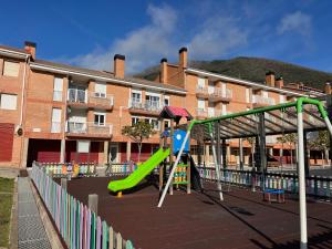 a playground with a slide in front of a building at Apartament reformat al Berguedà in Sant Jordi de Cercs