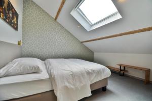 ein Schlafzimmer mit einem weißen Bett und einem Dachfenster in der Unterkunft Les Gîtes de Huy - 3 gîtes dans le centre de Huy in Huy