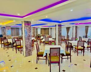 un restaurante con mesas y sillas blancas e iluminación púrpura en Staynest darjeeling near railway station en Darjeeling
