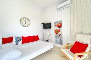 - une chambre avec un lit doté d'oreillers rouges et d'une horloge dans l'établissement Domniki's Sea House, à Asprovalta