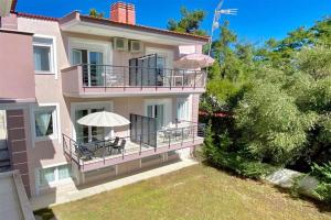 un grand bâtiment rose avec un balcon avec un parasol dans l'établissement Domniki's Sea House, à Asprovalta
