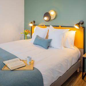 een bed met een dienblad met een boek en een kopje erop bij All Suites Appart Hotel Le Havre in Le Havre