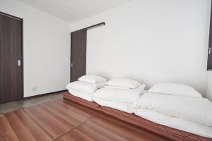 uma cama com almofadas brancas num quarto em 08 Resort Club -Theater- em Fujikawaguchiko