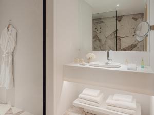 uma casa de banho branca com um lavatório e um espelho em The Roc Club em Atenas