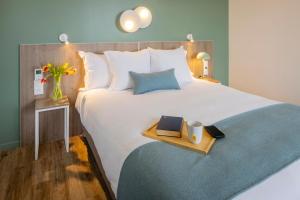 a bedroom with a bed with a tray with two books at All Suites Appart Hôtel - Le Havre Centre - Les docks in Le Havre