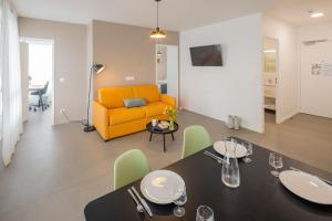 a dining room and living room with a yellow couch at All Suites Appart Hôtel - Le Havre Centre - Les docks in Le Havre